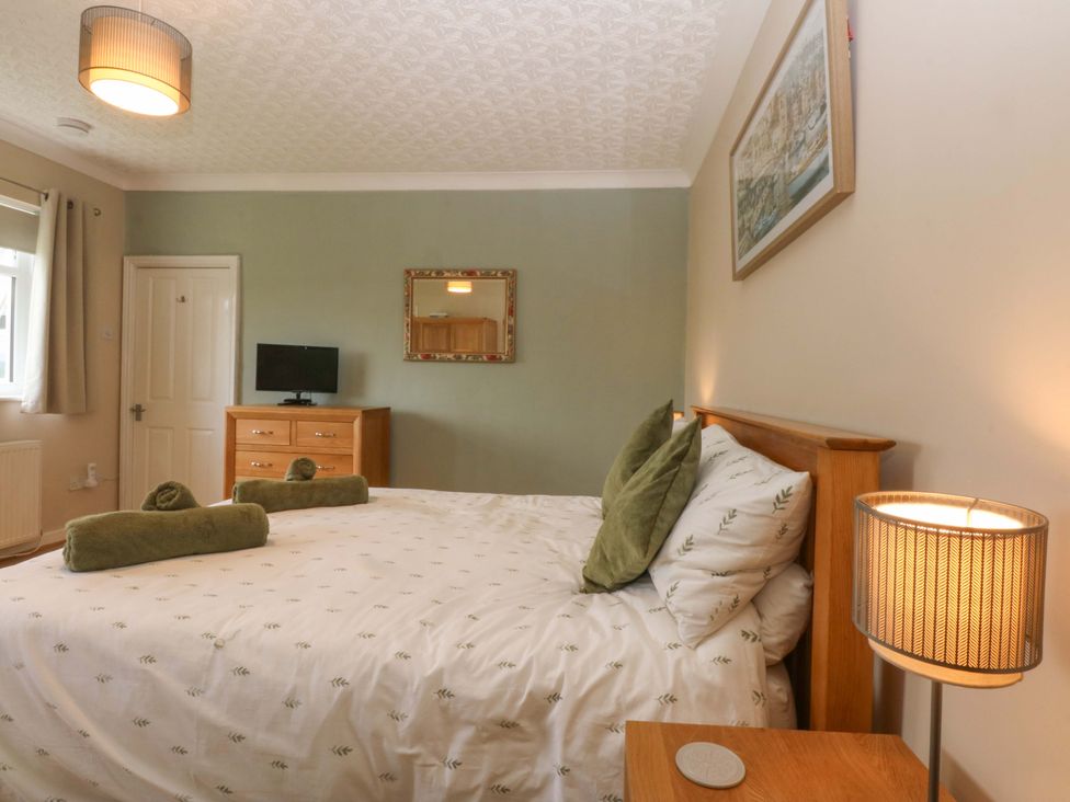 A bedroom with a bed and a television at Menai Cottage in Brynsiencyn