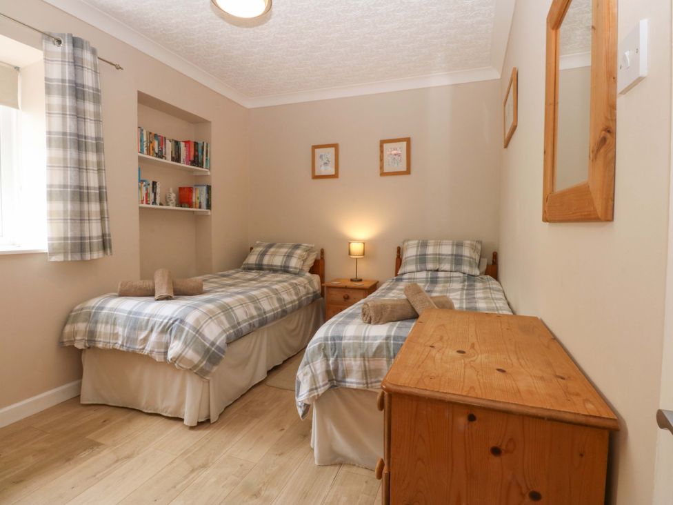A bedroom with two single beds and a bookshelf at Menai Cottage in Brynsiencyn