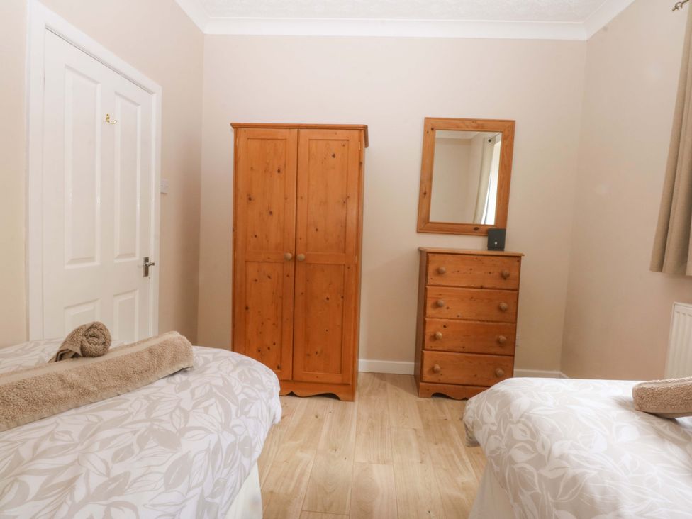 A bedroom with a wardrobe and mirror at Menai Cottage in Brynsiencyn