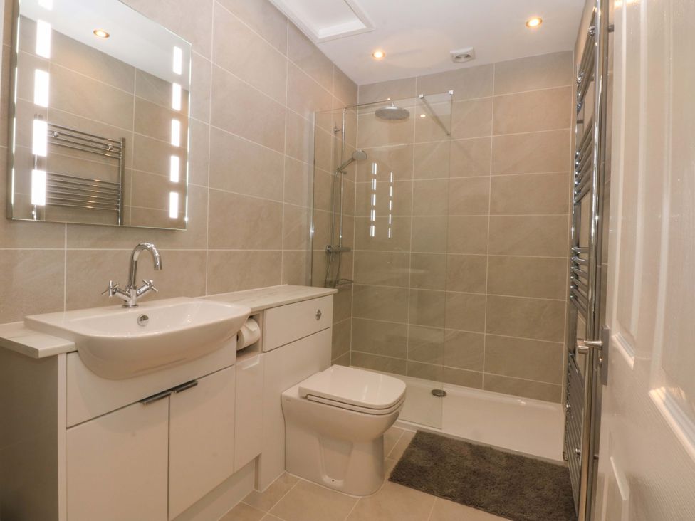 A bathroom with a sink, toilet, and shower at Menai Cottage in Brynsiencyn