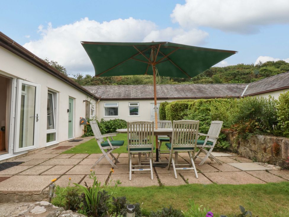 A garden with a table and chairs under a parasol at Menai Cottage in Brynsiencyn