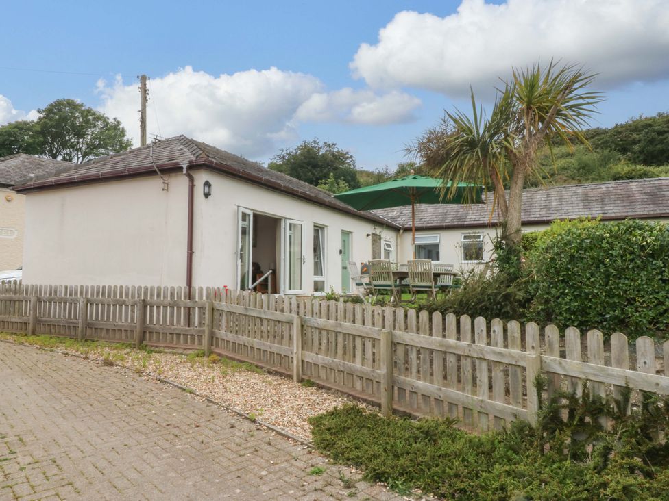 An outdoor area with a table and chairs and an umbrella at Menai Cottage in Brynsiencyn