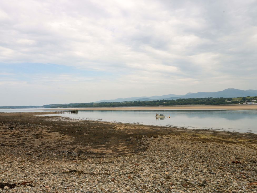 A coastal scene with water and a boat near the shore at Menai Cottage in Brynsiencyn