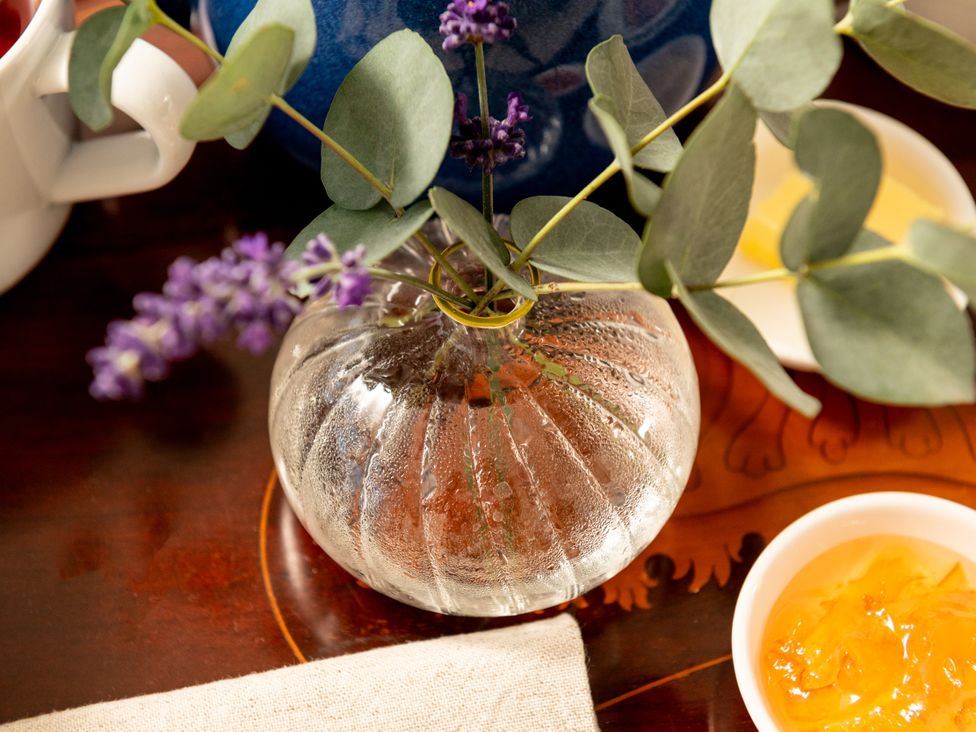 A glass vase with eucalyptus and lavender on a table at Summerfield in Deganwy