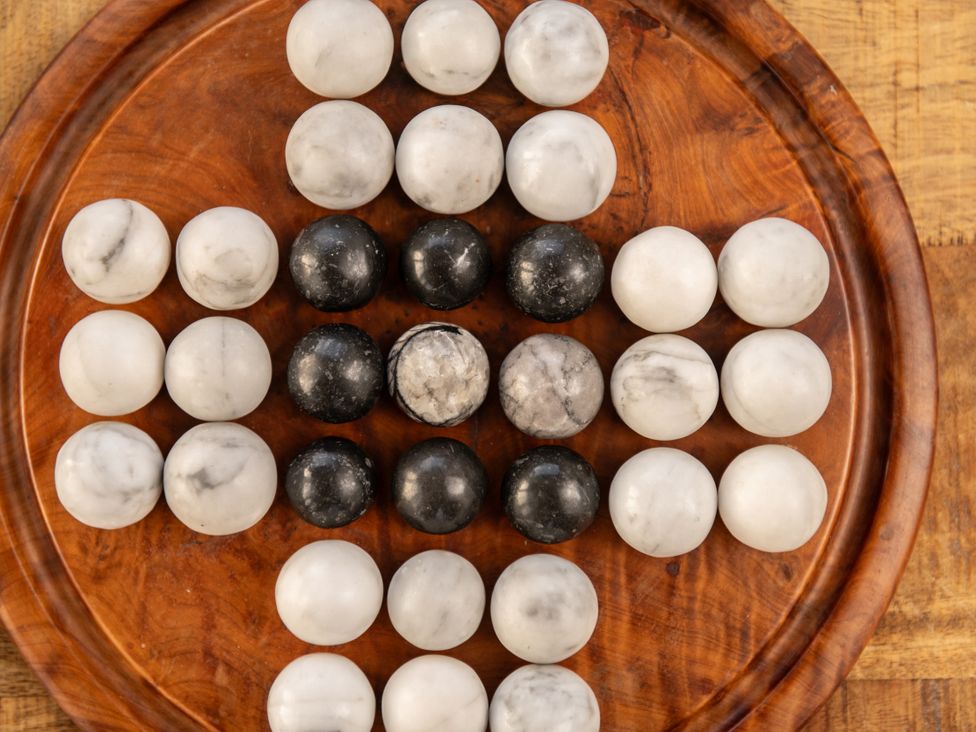 A wooden tray with black and white marble balls arranged in a pattern