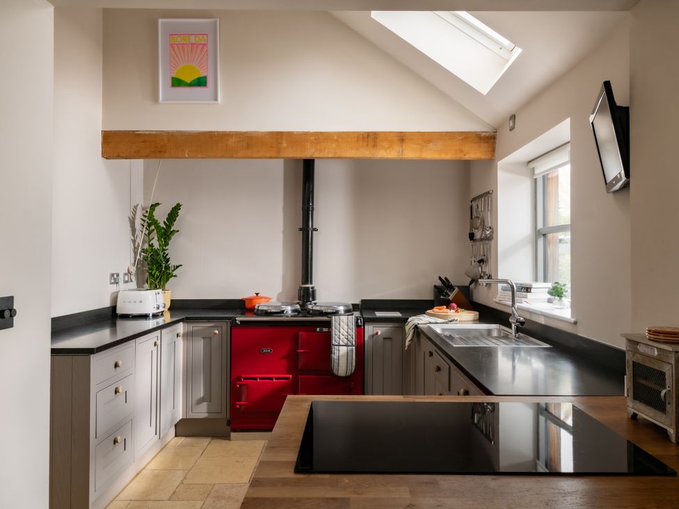 A kitchen with an island and a red cooker at Summerfield in Deganwy