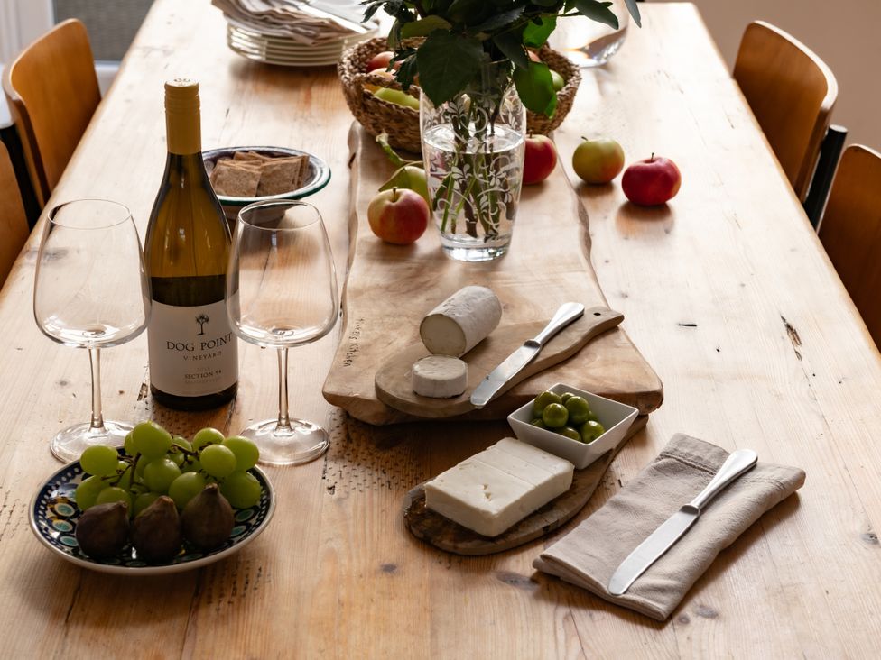 A dining table with wine glasses, cheese, grapes, and flowers at Summerfield in Deganwy