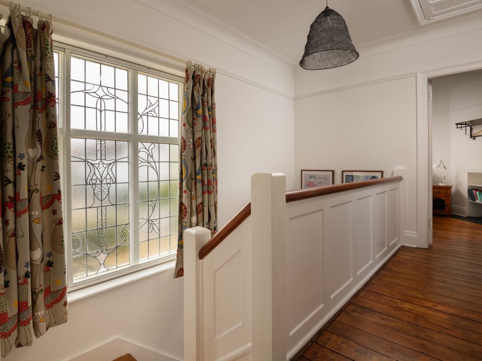 A hallway with a stained glass window and wooden railing at Summerfield in Deganwy