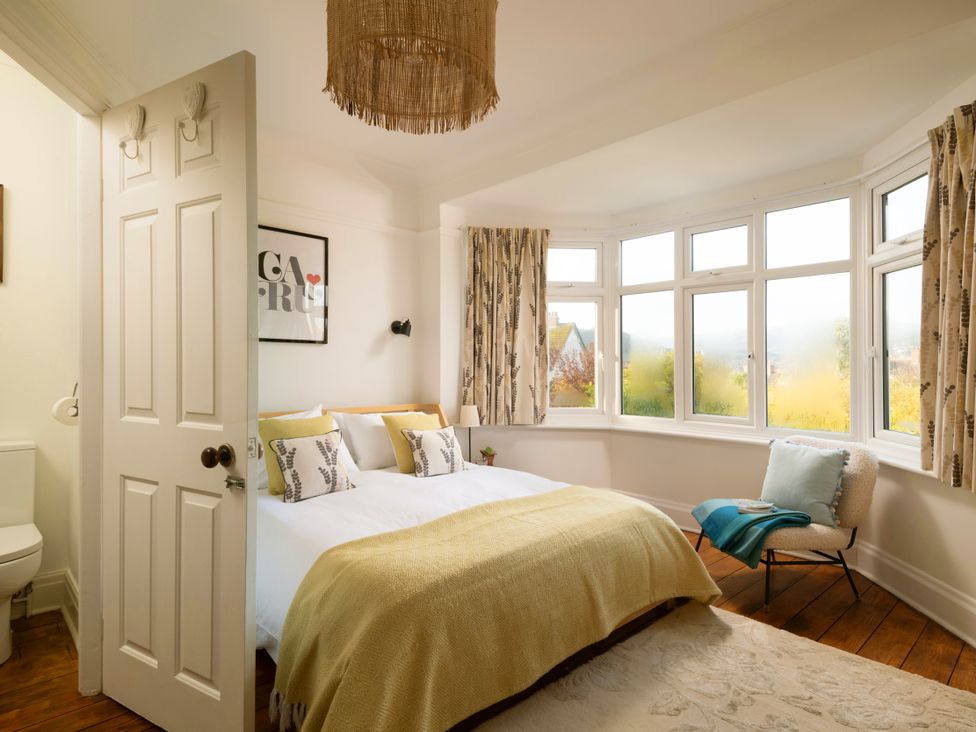 A bedroom with a bed and windows at Summerfield in Deganwy