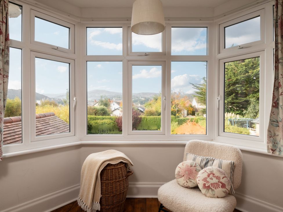 A snug with large windows and a chair at Summerfield in Deganwy