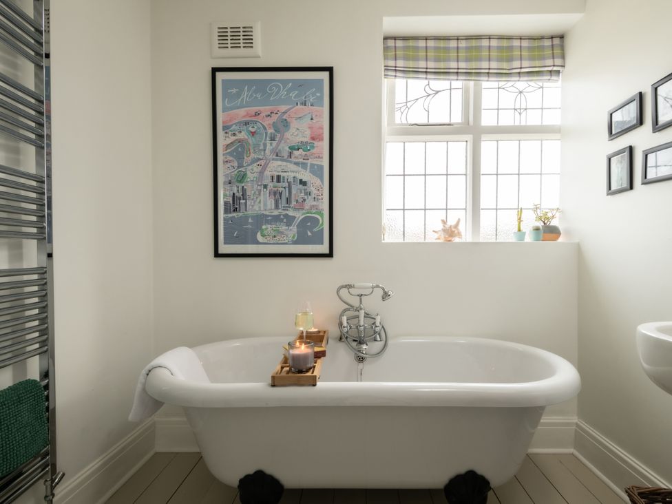 A bathroom with a bathtub and framed artwork at Summerfield in Deganwy