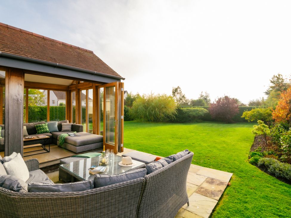 A conservatory with seating and a table overlooking the garden at Summerfield in Deganwy