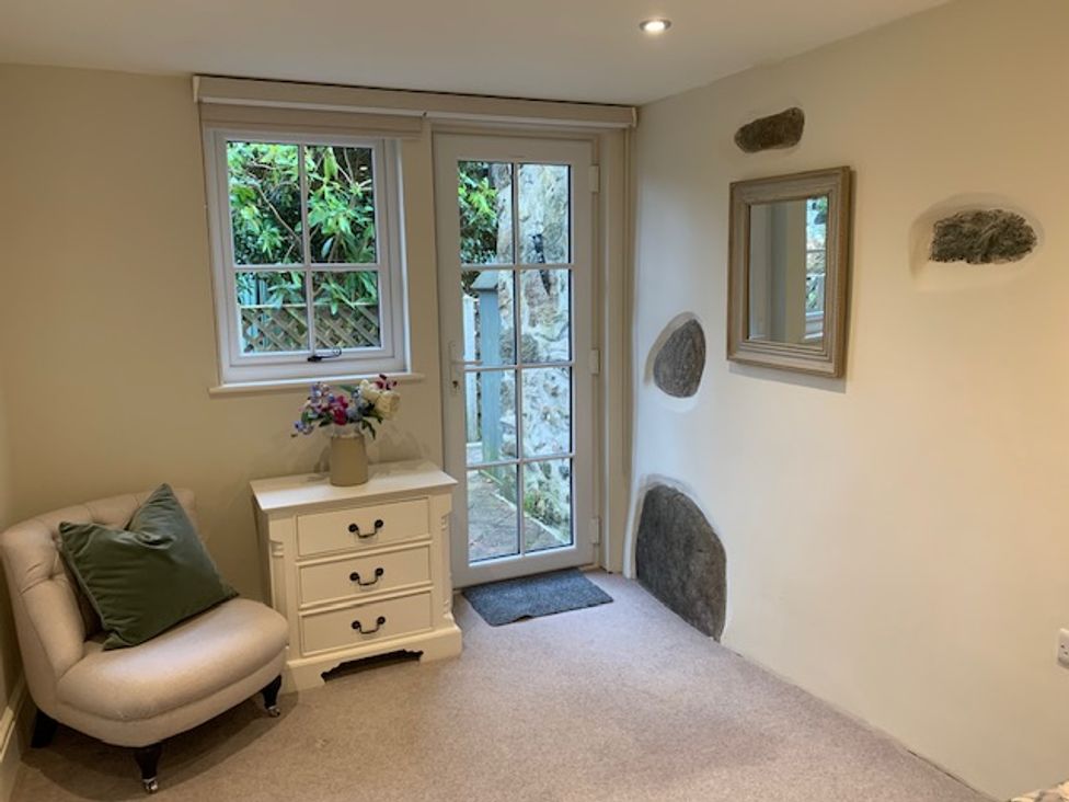 A room with a chair, table, and door at The Honey Pot in Garndolbenmaen