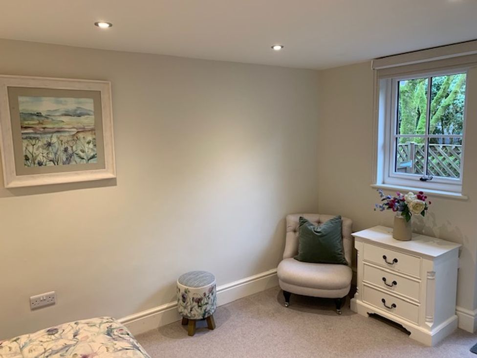 A bedroom with a chair and dresser at The Honey Pot in Garndolbenmaen