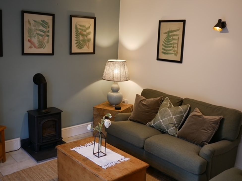 A living room with a sofa and artwork on the wall at The Honey Pot in Garndolbenmaen