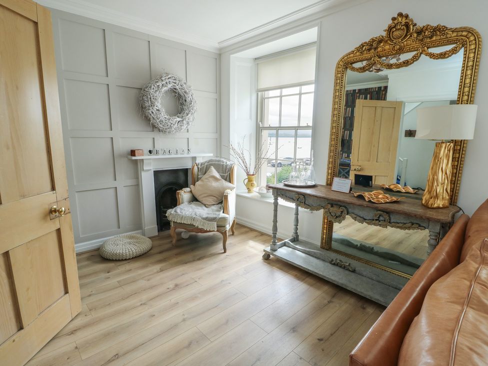 A living room with a fireplace and a chair at Tri Raglan Mawr in Beaumaris