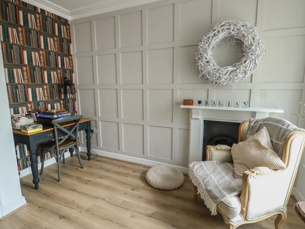 A snug with a desk, chair and a fireplace at Tri Raglan Mawr in Beaumaris
