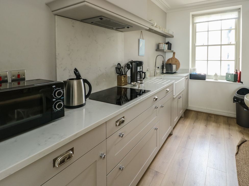 A kitchen with a microwave, kettle, coffee maker, and sink at Tri Raglan Mawr in Beaumaris