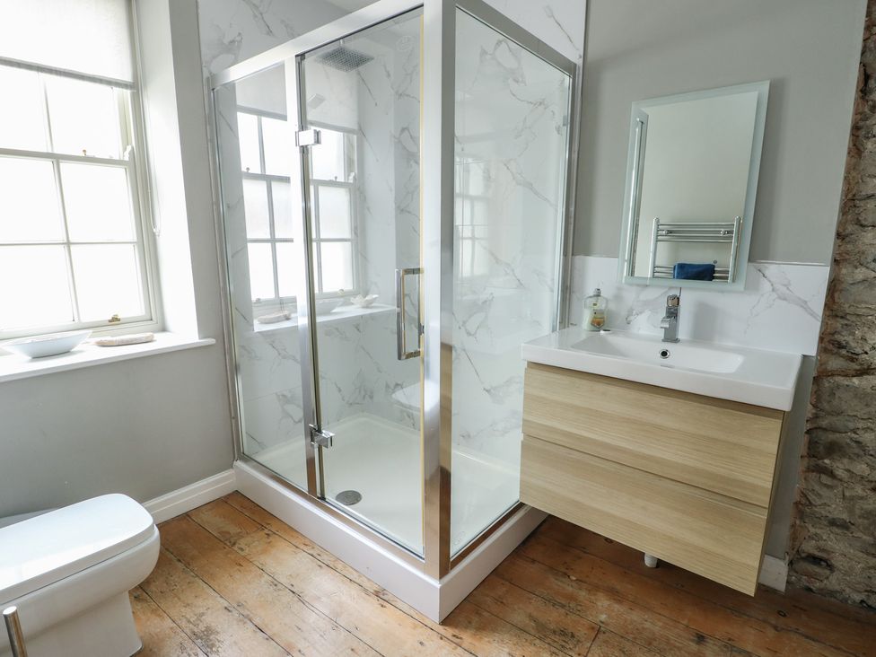A bathroom with a shower enclosure and wooden sink unit at Tri Raglan Mawr Beaumaris