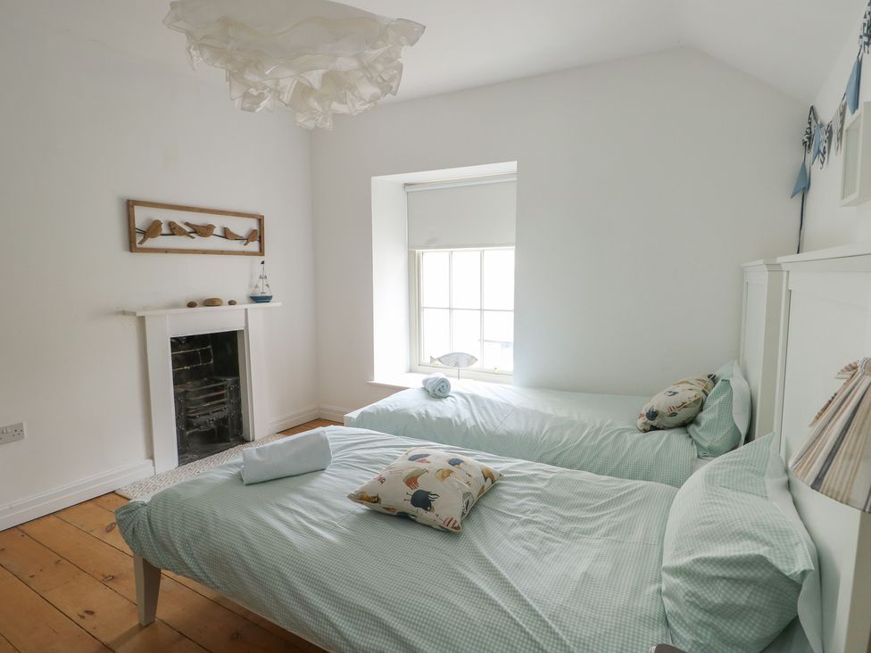 A bedroom with two single beds and a window at Tri Raglan Mawr Beaumaris