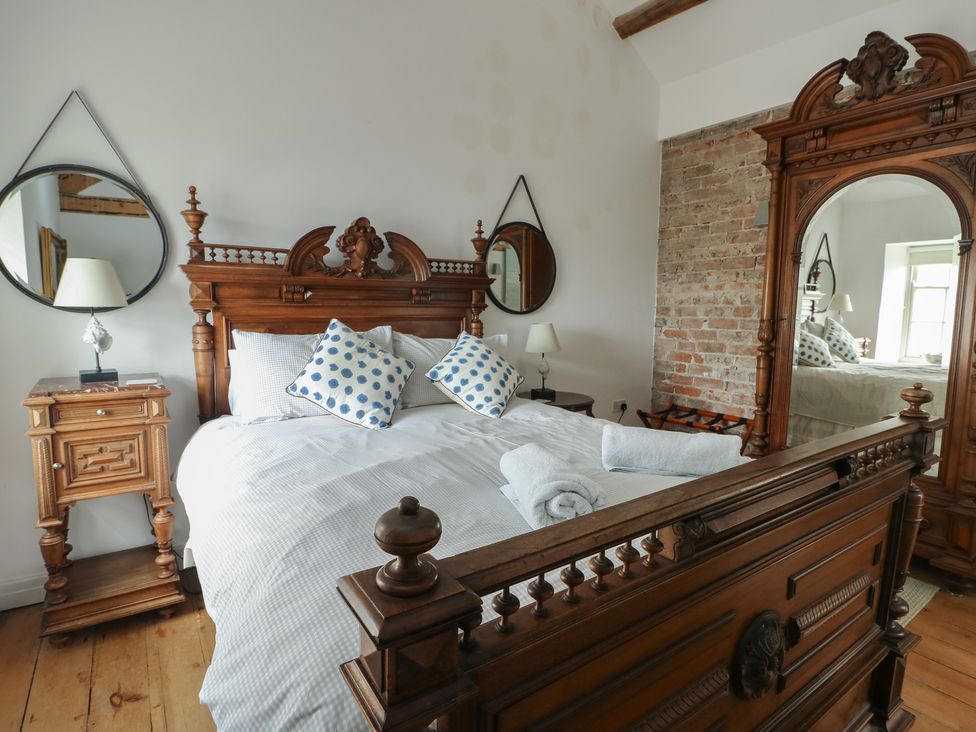 A bedroom with a bed and nightstand at Tri Raglan Mawr in Beaumaris