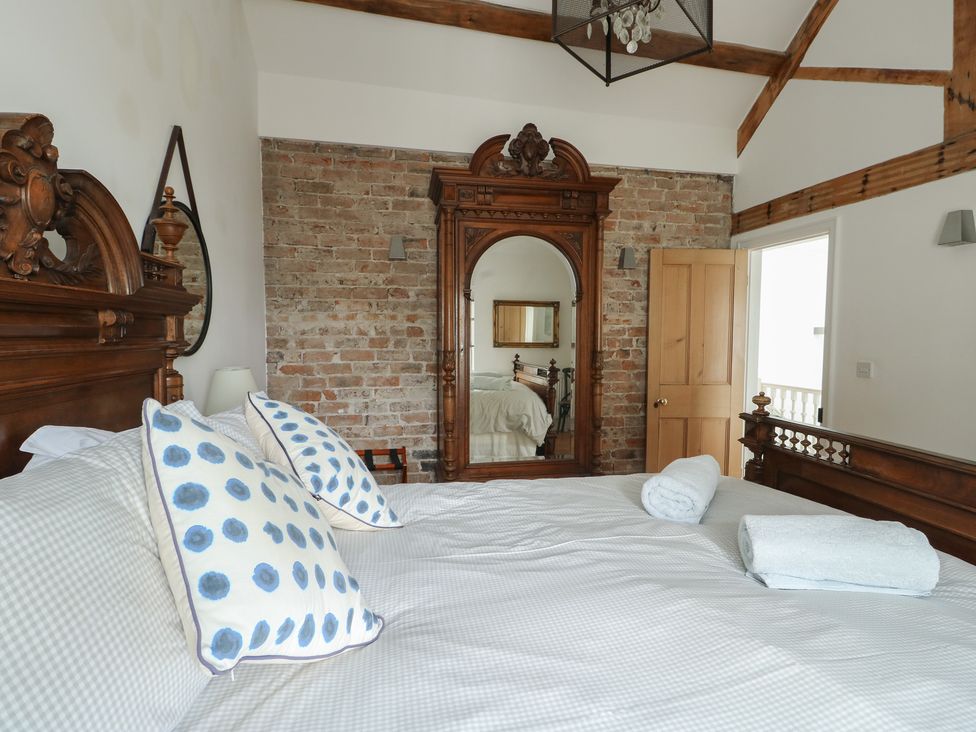 A bedroom with a bed and a mirror at Tri Raglan Mawr Beaumaris