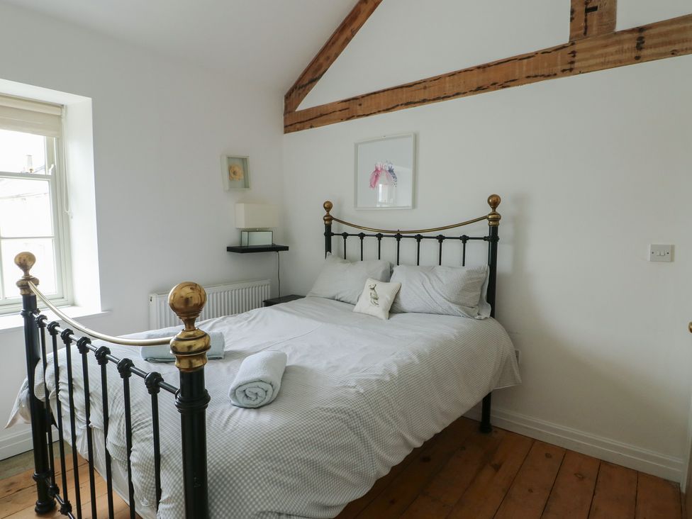A bedroom with a metal bed frame and window at Tri Raglan Mawr in Beaumaris