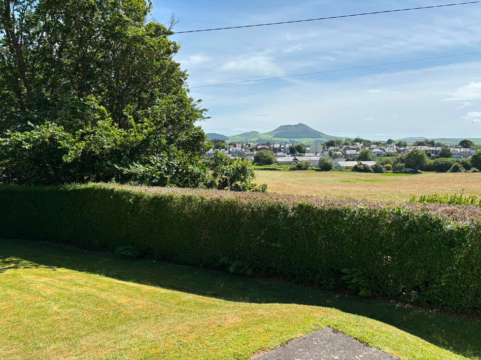 A garden with a hedge and a view of houses and mountains at Ty Bryn - Nefyn Morfa Nefyn