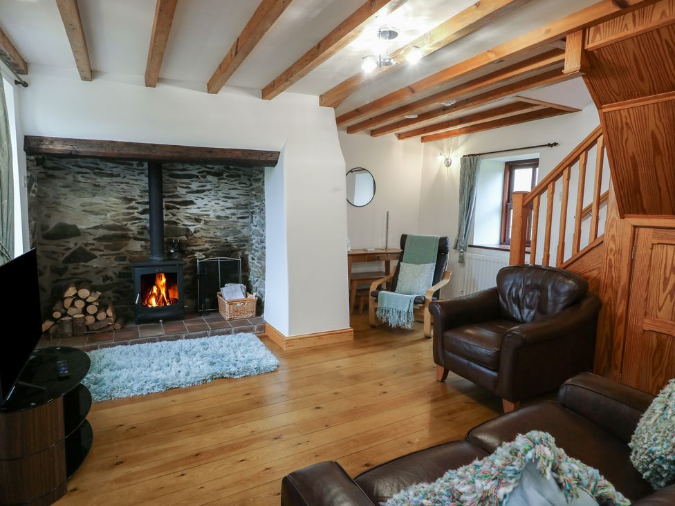 A living room with a fireplace and wooden beams at Tyn y Mynydd in Bull Bay