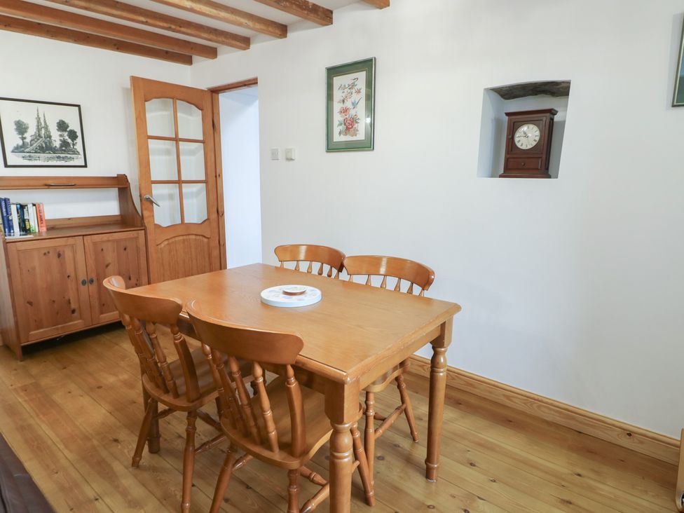 A dining room with a wooden table and chairs at Tyn y Mynydd in Bull Bay