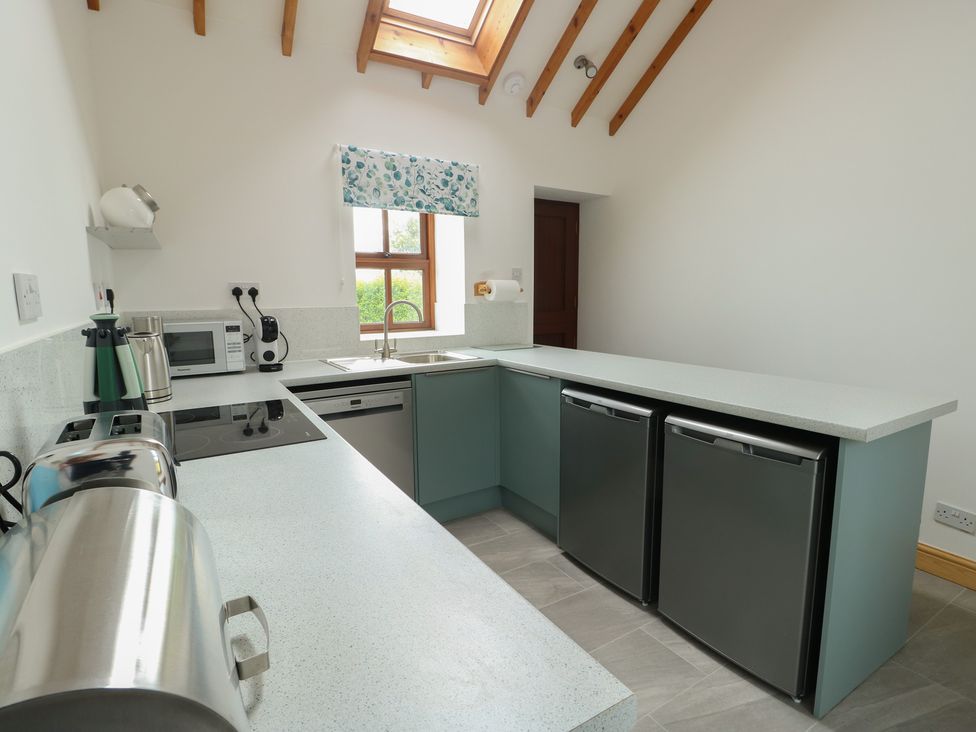 A kitchen with appliances and a sink at Tyn y Mynydd Bull Bay