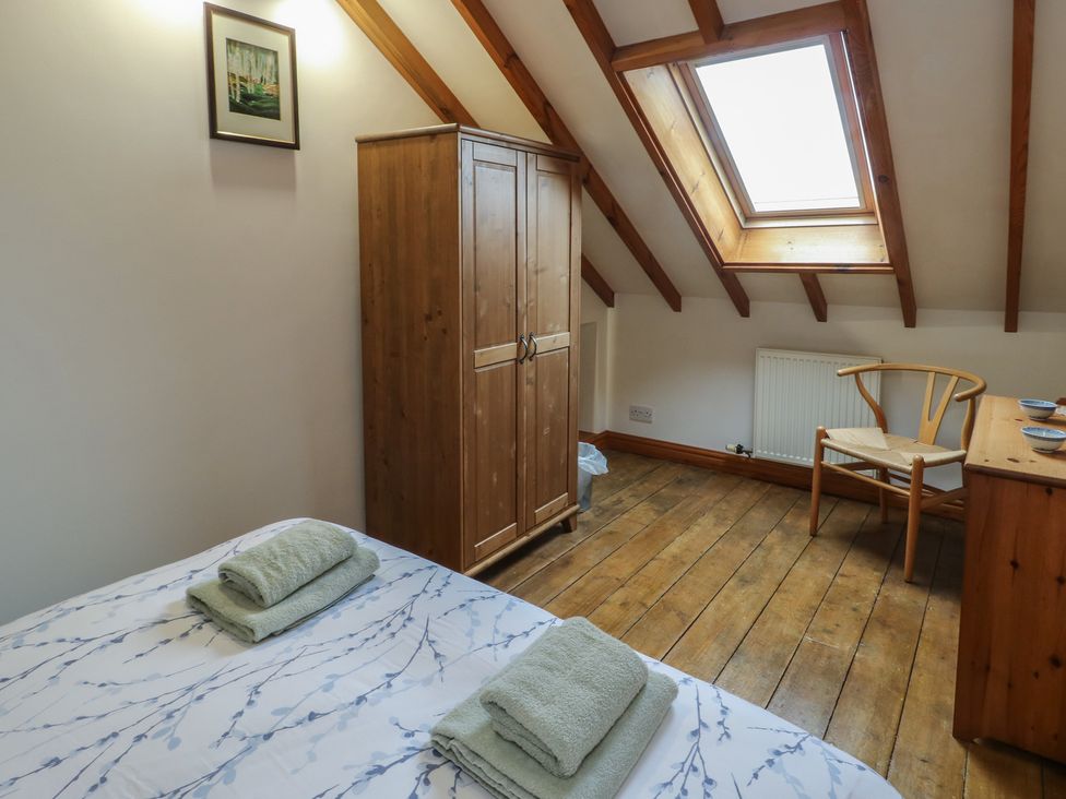 A bedroom with a bed and wardrobe at Tyn y Mynydd in Bull Bay