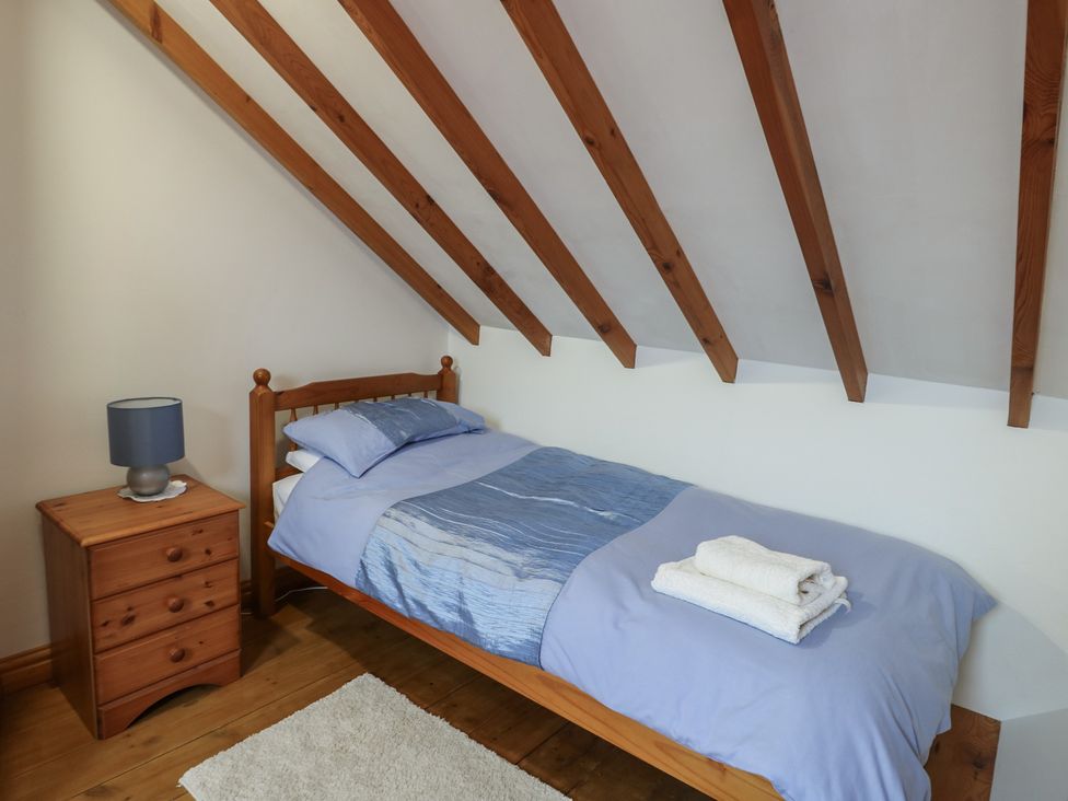 A bedroom with a single bed and nightstand at Tyn y Mynydd Bull Bay