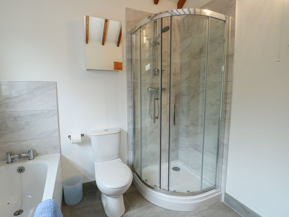 A bathroom with a shower and bathtub at Tyn y Mynydd Bull Bay