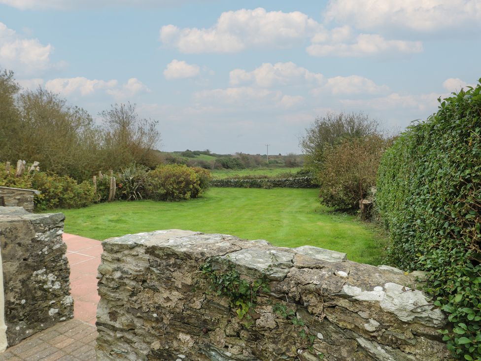 A garden with a stone wall and grass at Tyn y Mynydd in Bull Bay