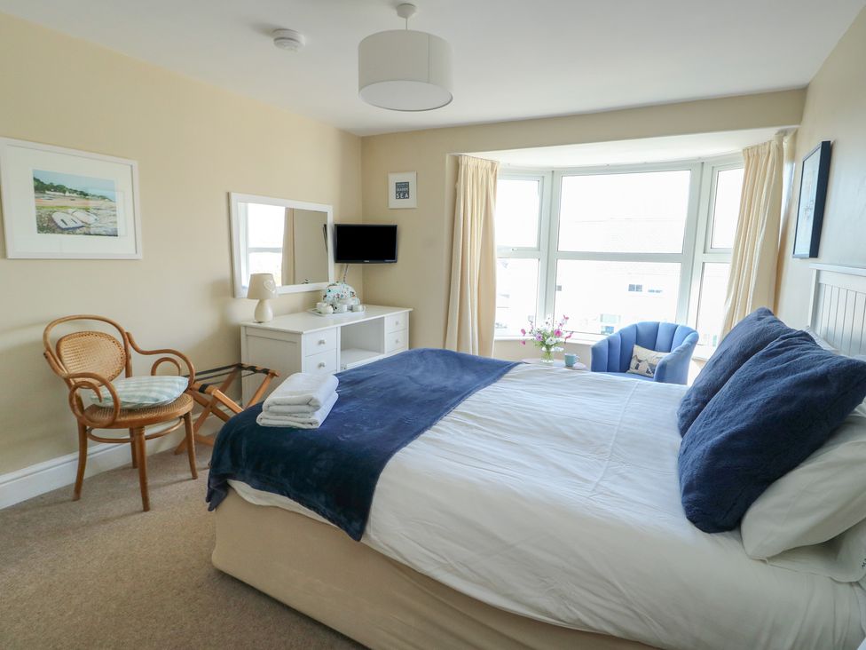 A bedroom with a bed and chair at West View Rhosneigr