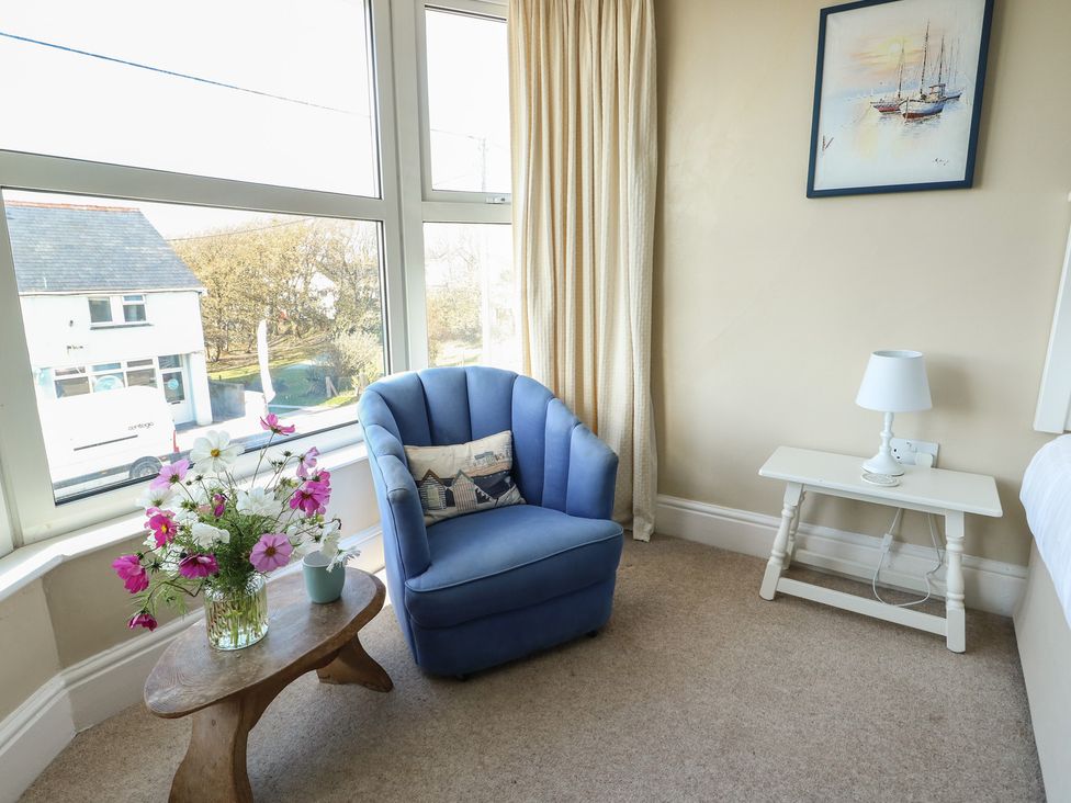 A bedroom with an armchair and a flower arrangement at West View in Rhosneigr