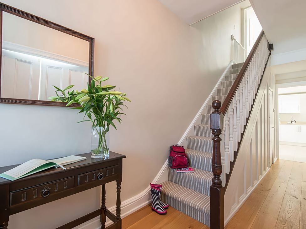 A hallway with stairs and flowers on a console table at West View in Rhosneigr