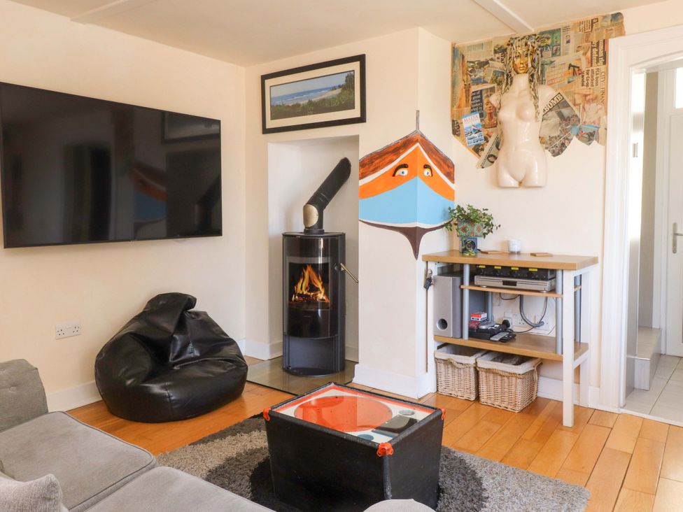 A living room with a mounted TV bean bag stove and a table with baskets and a decorative mannequin torso at Y Stabl in Criccieth