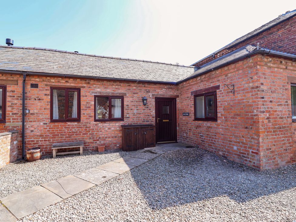 A brick exterior with a door, windows, and gravel area at Clwyd Cottage in St Asaph