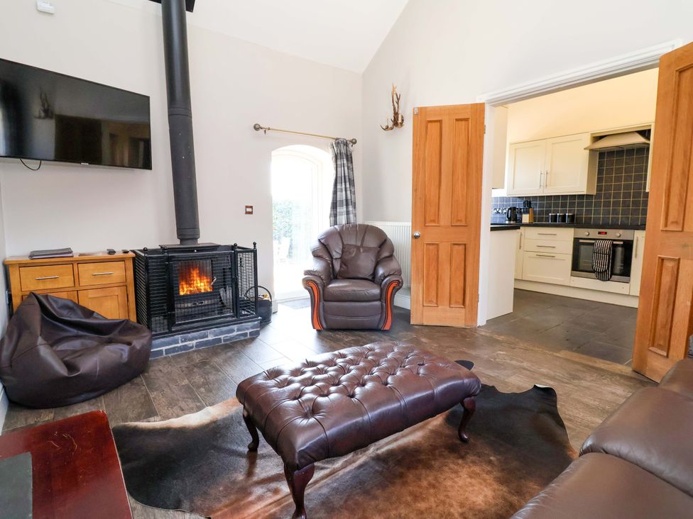 A living room with a fireplace and kitchen at Clwyd Cottage in St Asaph