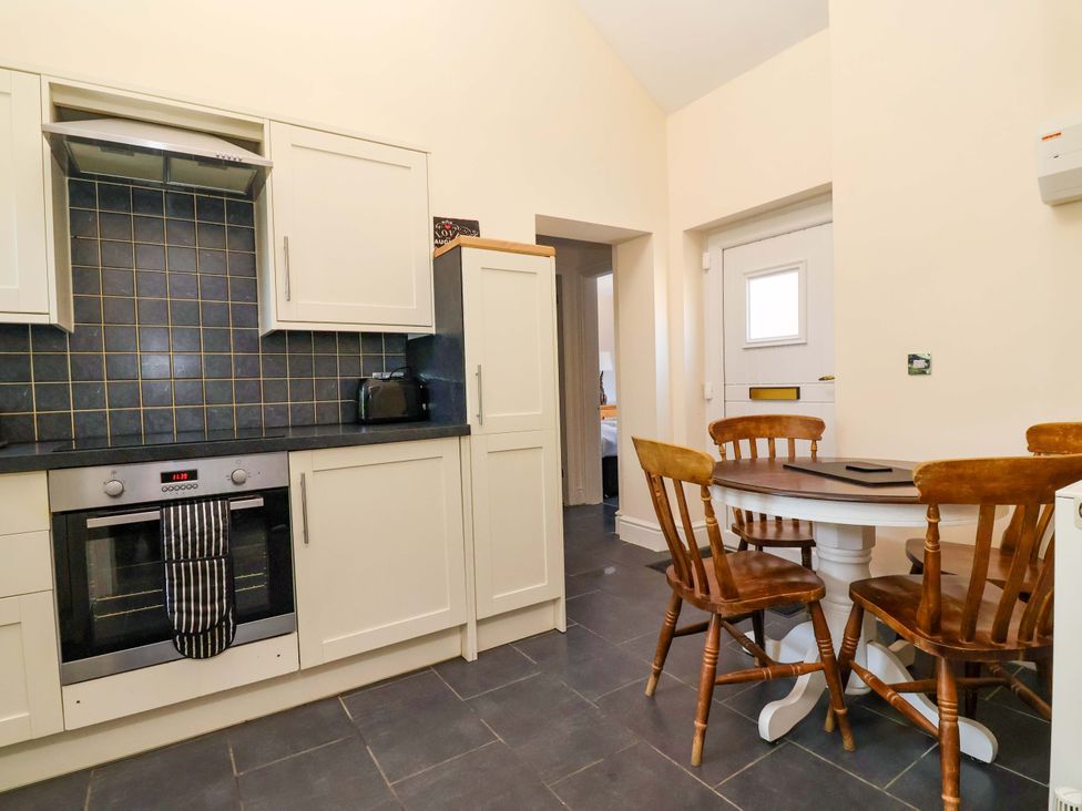 A kitchen with cabinets, a table, and chairs at Clwyd Cottage in St Asaph
