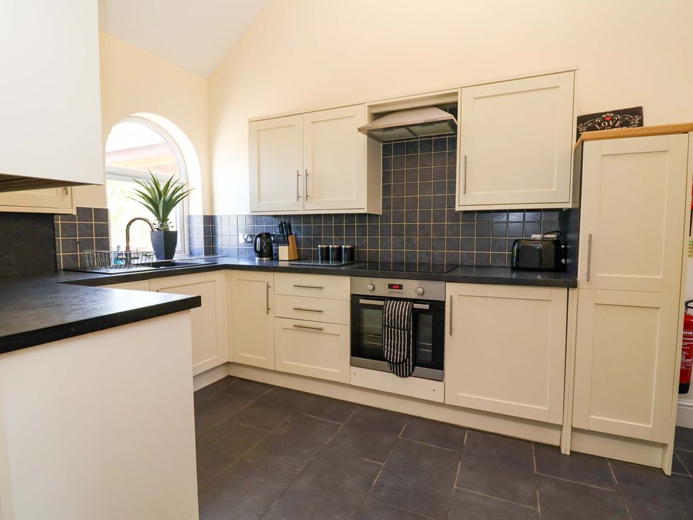 A kitchen with cabinets, oven, and sink at Clwyd Cottage in St Asaph