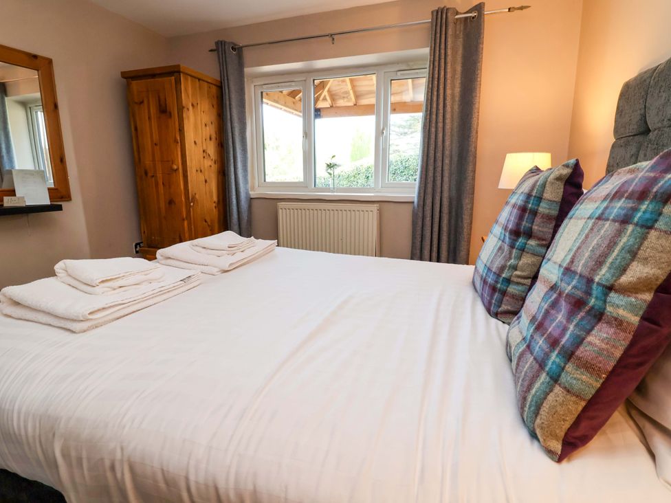 A bedroom with a bed and wardrobe at Clwyd Cottage St Asaph