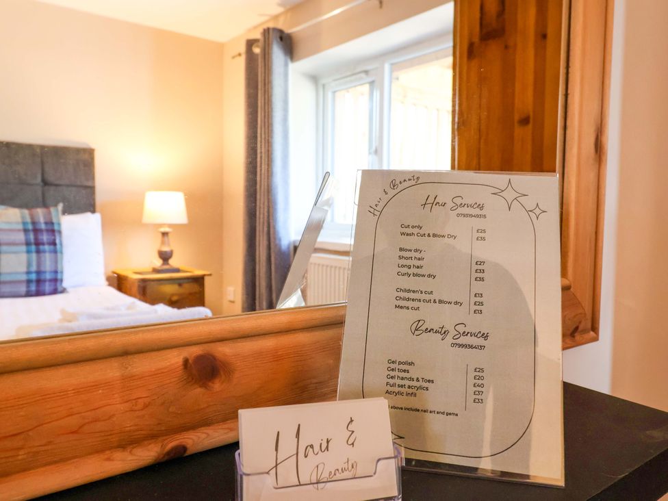 A bedroom with a bed and hair services menu at Clwyd Cottage in St Asaph