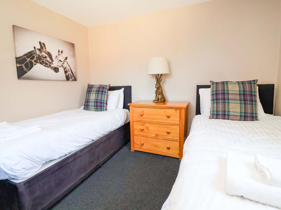 A bedroom with twin beds and a wooden nightstand at Clwyd Cottage St Asaph