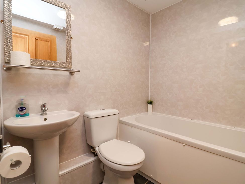 A bathroom with a sink, toilet, and bath tub at Clwyd Cottage St Asaph