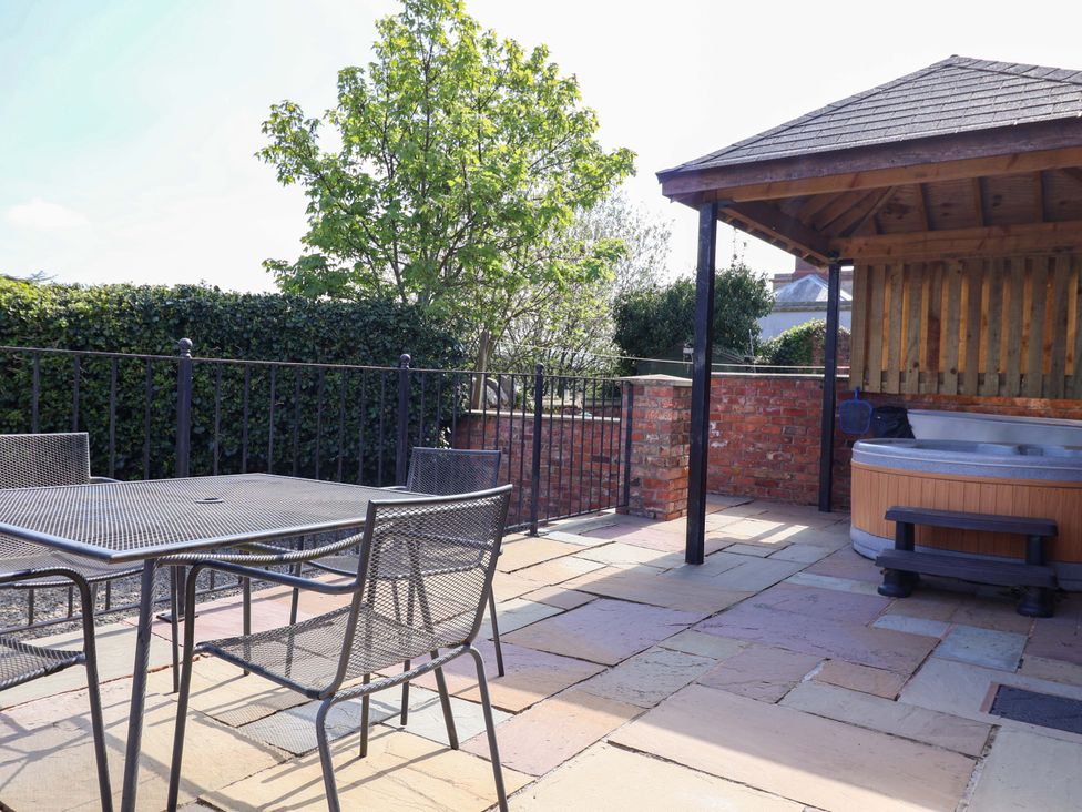 An outdoor area with a table, chairs, and a hot tub at Clwyd Cottage in St Asaph