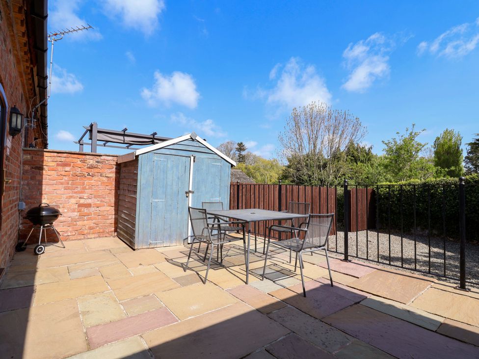 A garden with a table and chairs next to a shed at Clwyd Cottage in St Asaph