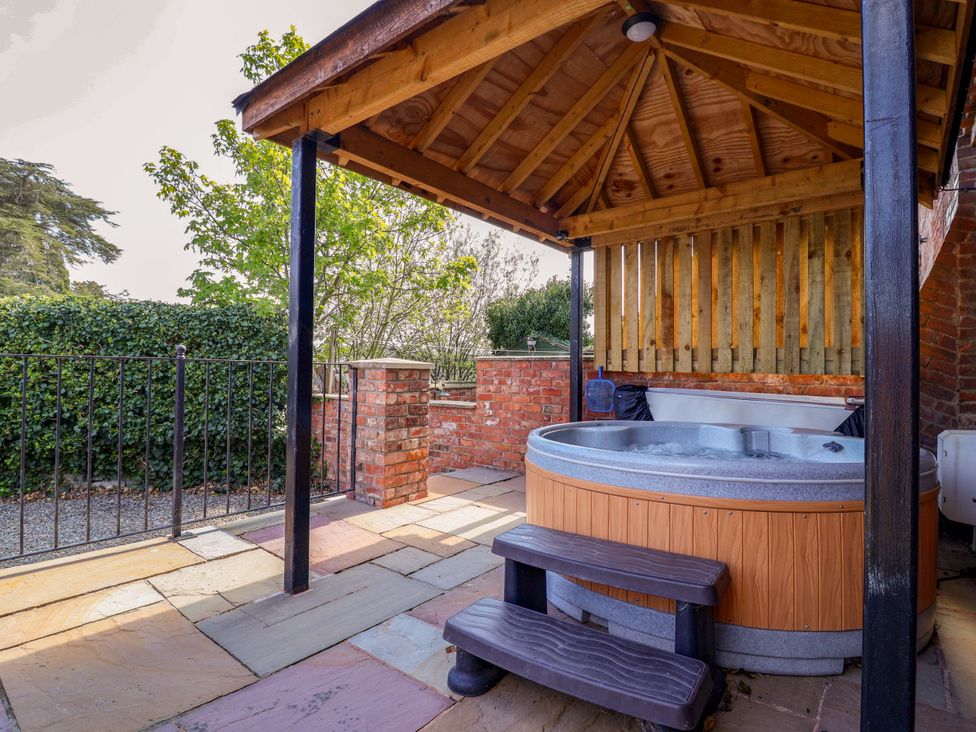 An outdoor area with a hot tub and wooden bench at Clwyd Cottage St Asaph